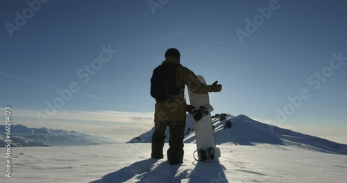 Freeride snowboarder high in the mountains. Extreme off-trail snowboarding down the untouched mountain terrain. Walking climbing the mountain ridge. Active lifestyle, adventure, winter sport concept photo