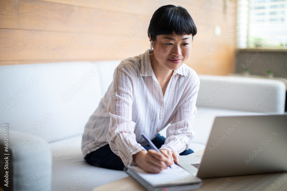 Young Asian woman talking on a video chat from a laptop at home Young Asian woman talking on a video chat from a laptop at home