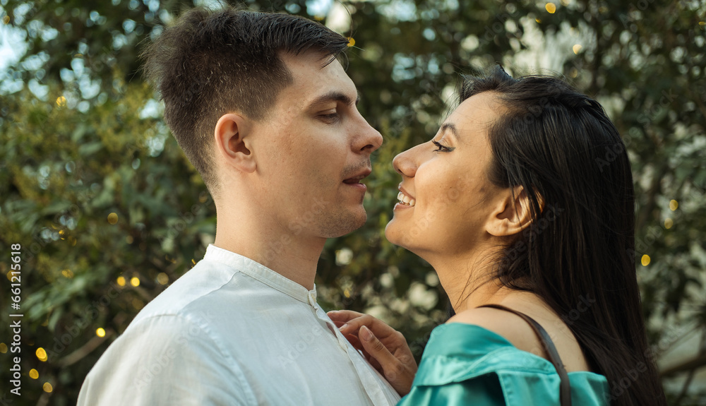 Fototapeta premium Young happy couple in love of different nationality hugging and kissing in the park. Asian woman and european man.