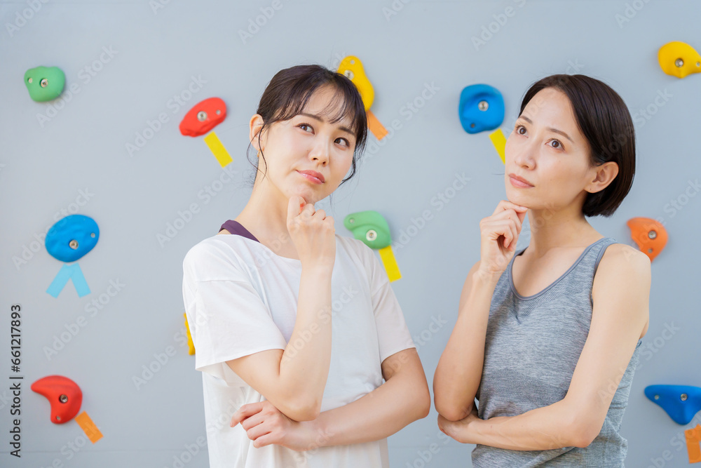 ボルダリングジムで考え事をする女性