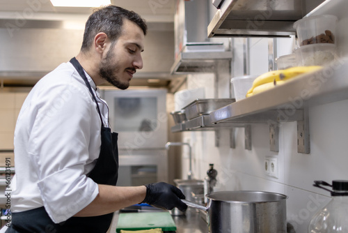 Ethnic arab chef working in the restaurant kitchen with black gloves on his hands