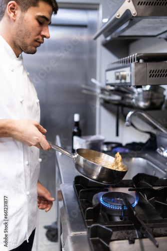 Vertical photo of a young chef cooking a risoto in the pan