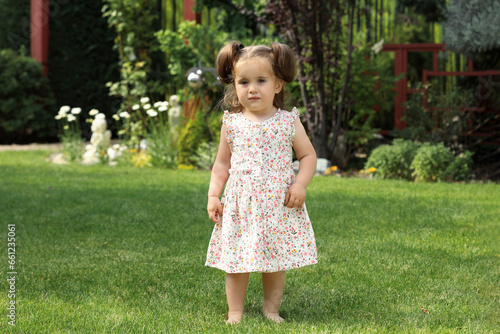 Cute little girl walking on green grass in park