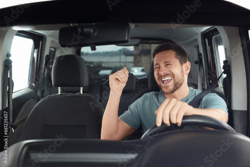 Listening to radio. Handsome man enjoying music in car, view through windshield © New Africa