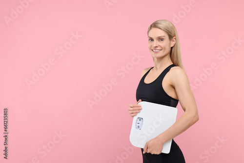 Slim woman holding scales on pink background, space for text. Weight loss