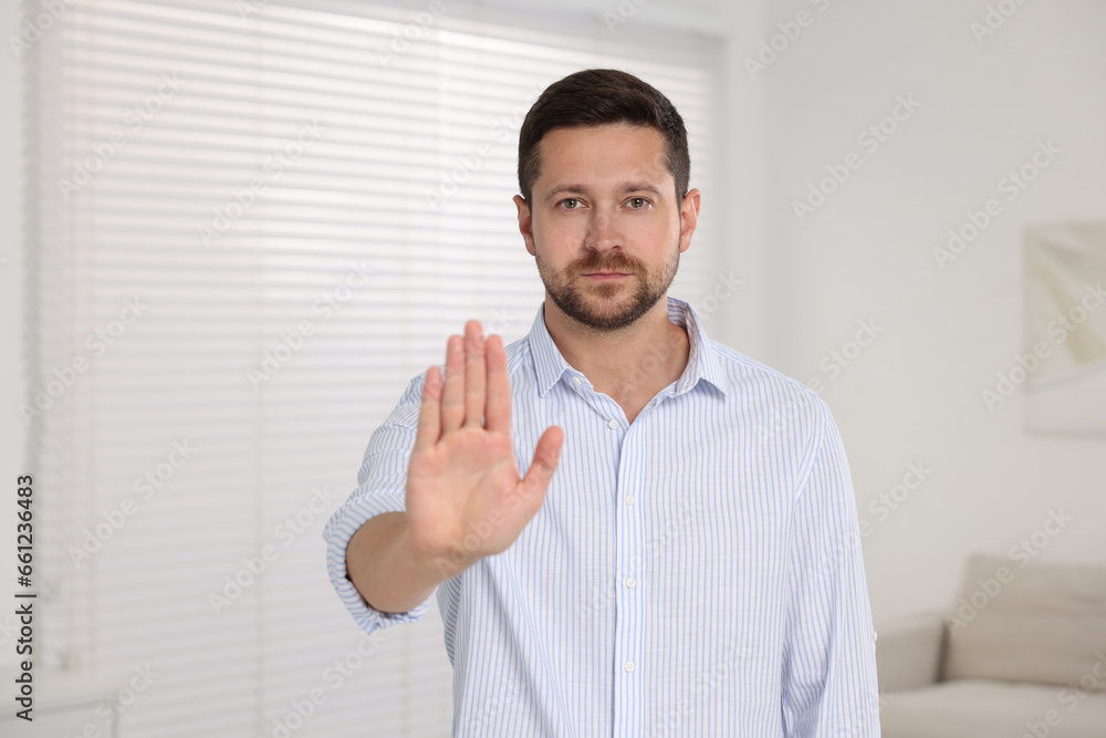 Handsome man showing stop gesture at home Handsome man showing stop gesture at home