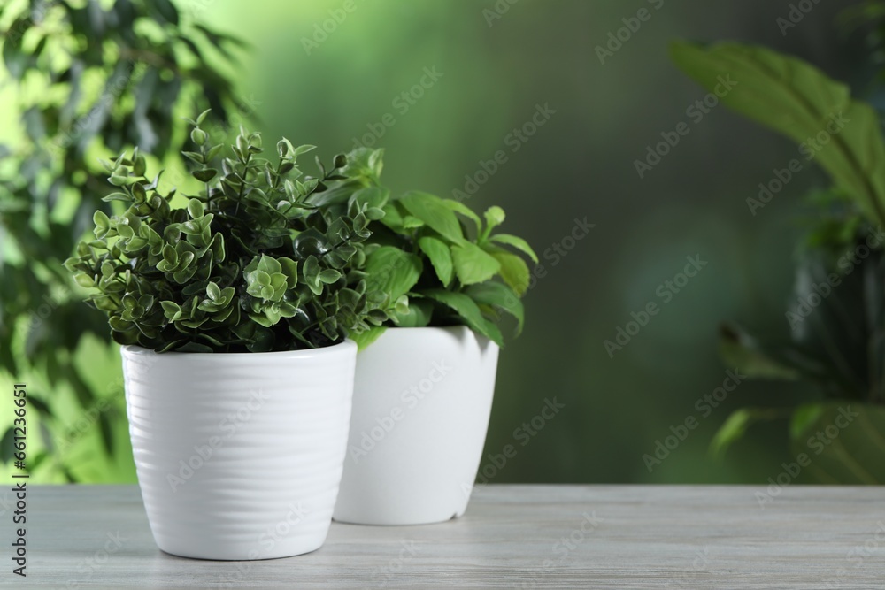 Fototapeta premium Different artificial potted herbs on white wooden table outdoors, space for text