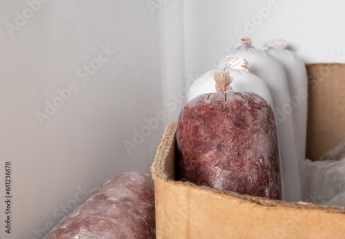 Raw food sausages for dogs in freezer. Raw meat diet or barf for dogs, cats and pets. Organic human grade ground chicken and beef with muscle, bone and organs. Selective focus. photo