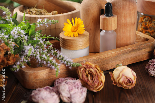 Jar, bottles of essential oils and different herbs on wooden table