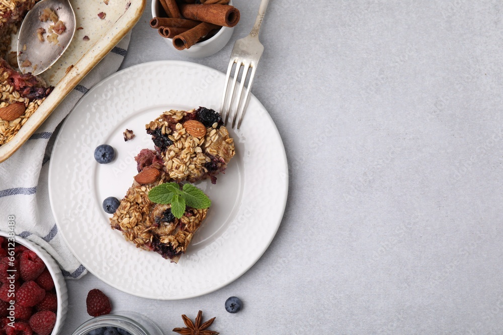 Tasty baked oatmeal with berries and almonds on light grey table, flat lay. Space for text