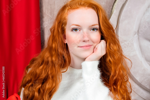 Christmas portrait of a beautiful young red-haired woman with bushy hair wearing a white jumper