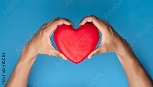 Hands holding a red heart on a blue background