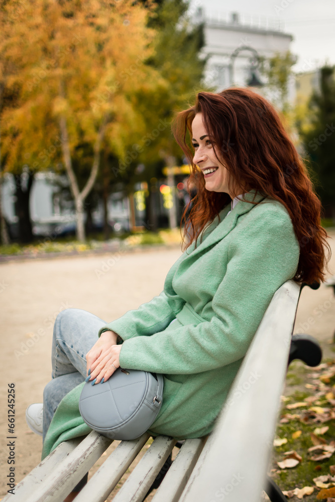a girl with red hair surrounded by yellow foliage. autumn walk in the city. portrait of a woman a girl with red hair surrounded by yellow foliage. autumn walk in the city. portrait of a woman