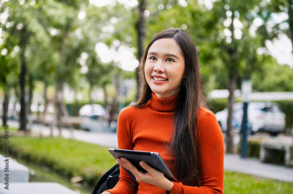 Asian college students sit and smile at a park on campus