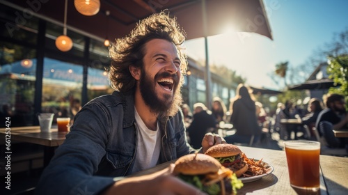 A happy man eating a burger in an outdoor restaurant as a Breakfast photo