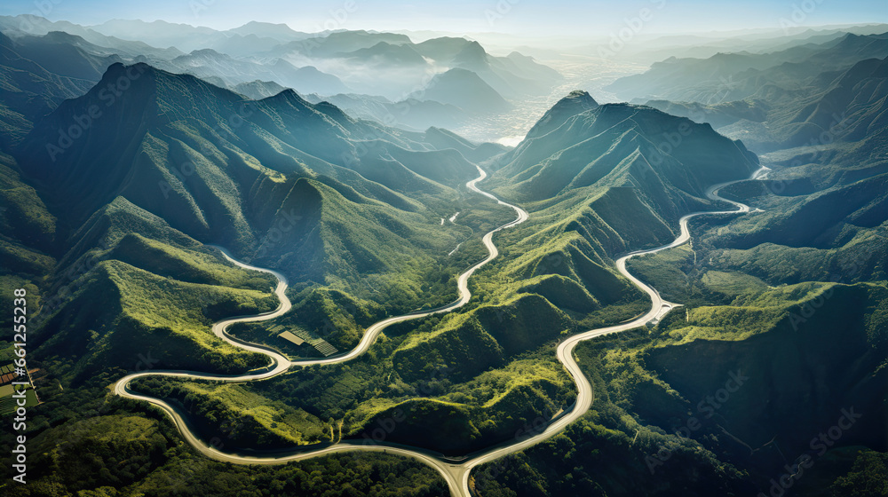 An awe-inspiring aerial view of a winding road cutting through mountains or a coastal landscape, depicting nature's grandeur. 