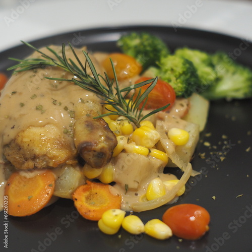 Succulent roasted chicken, baked potatoes, mushroom sauce, and corn on a plate