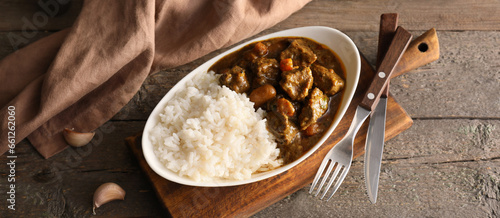 Plate with tasty curry and rice on wooden background