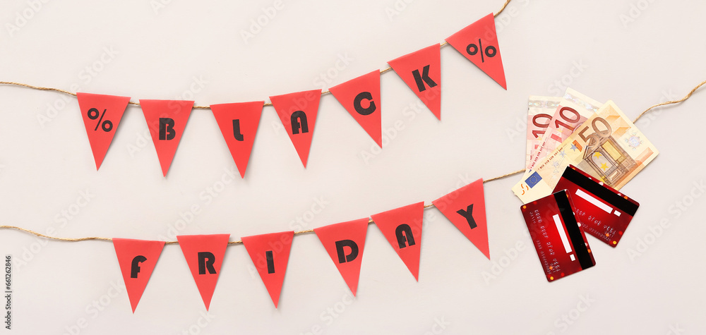 Credit cards, money and garland with text BLACK FRIDAY on light background Credit cards, money and garland with text BLACK FRIDAY on light background