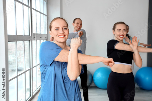 Sporty young woman training with group in gym