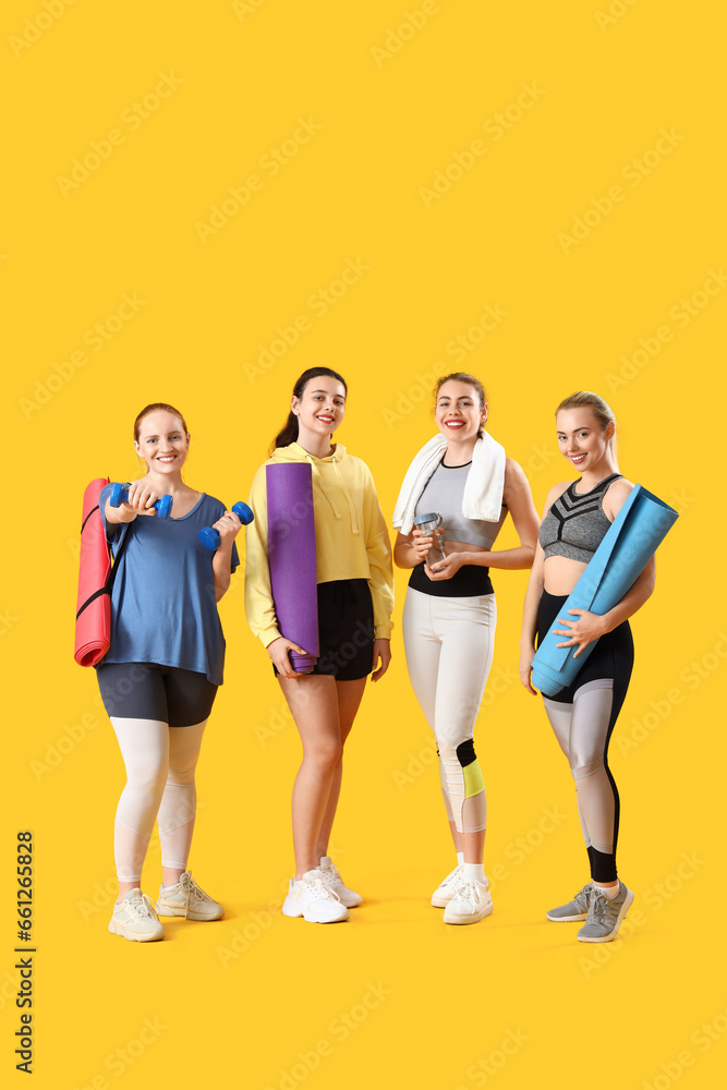 Fototapeta premium Sporty young women with equipment on yellow background