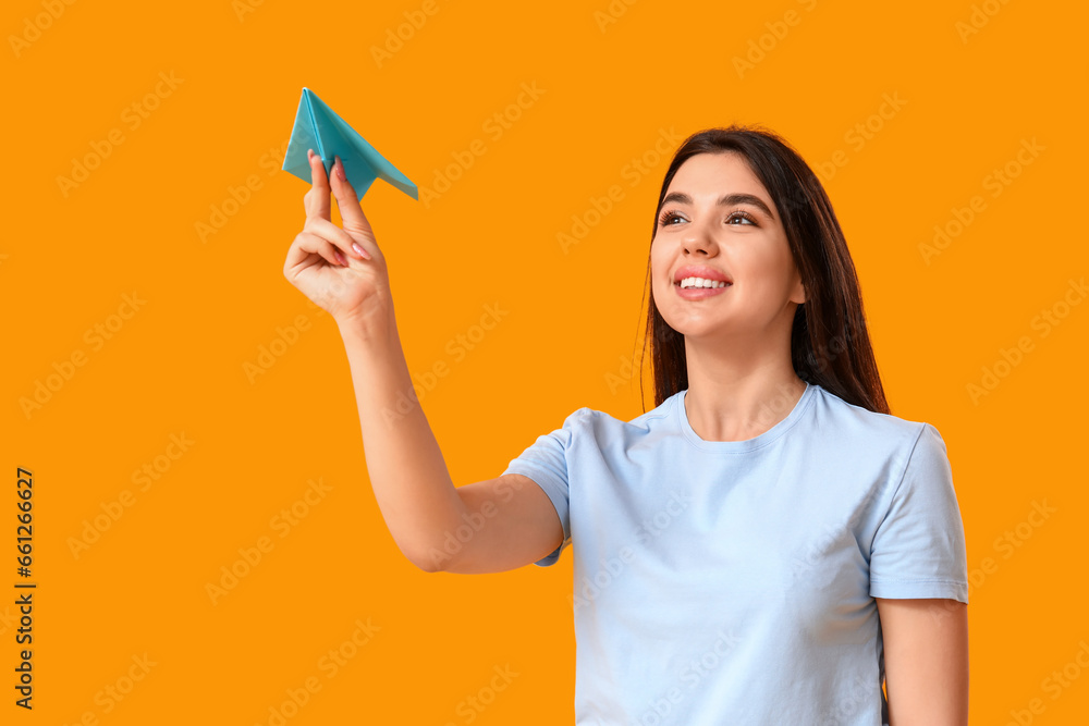 Young woman with paper plane on yellow background Young woman with paper plane on yellow background