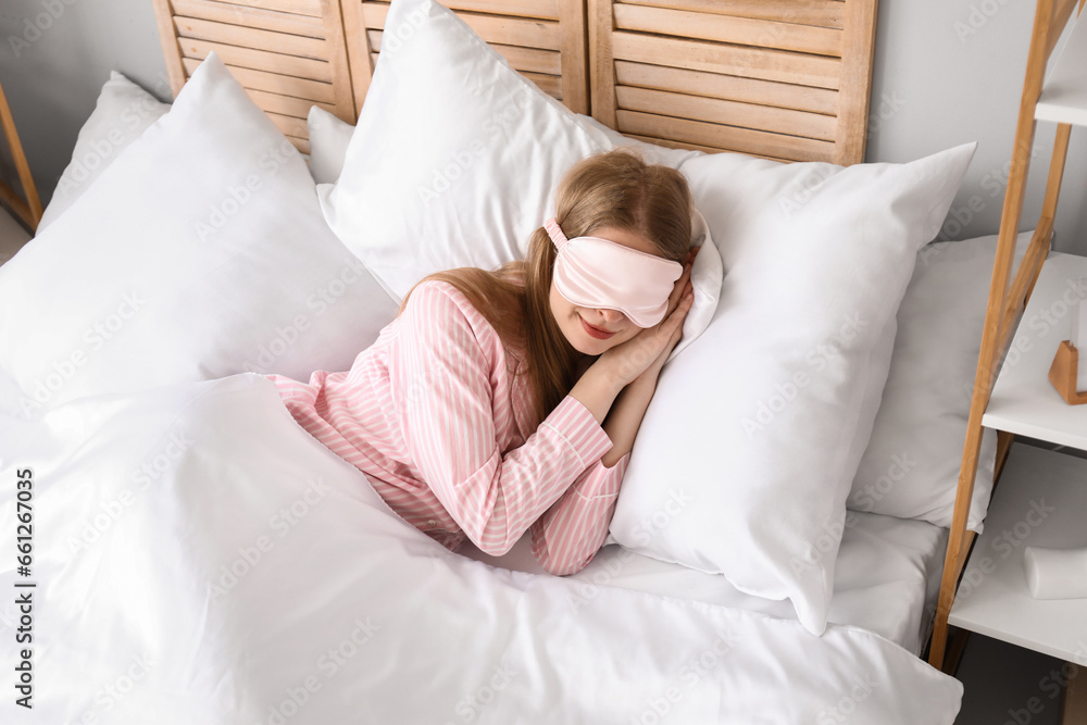 Young woman with sleeping mask lying on pillows in bed Young woman with sleeping mask lying on pillows in bed