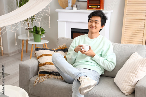 Young Asian man with cup of...