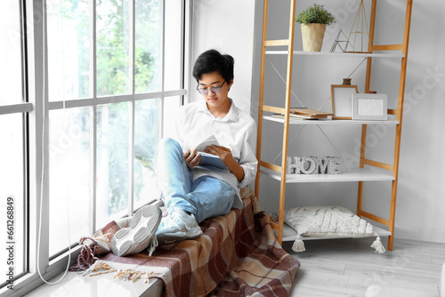 Young Asian man reading boo...