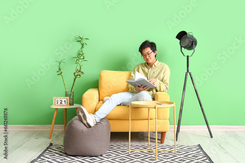 Young Asian man reading boo...