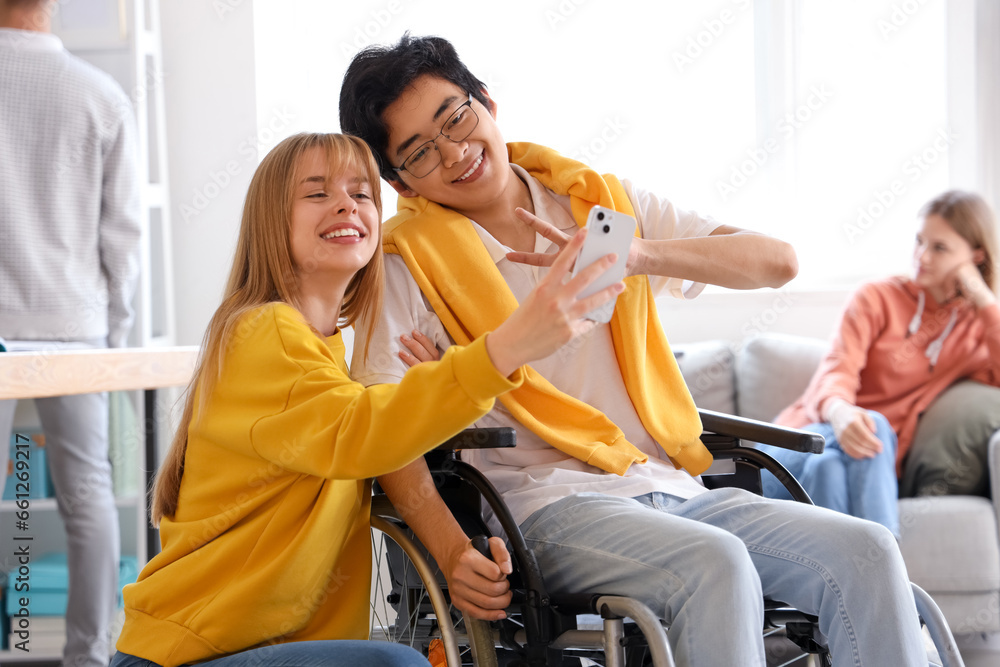 Teenage girl with her classmate in wheelchair taking selfie at school Teenage girl with her classmate in wheelchair taking selfie at school