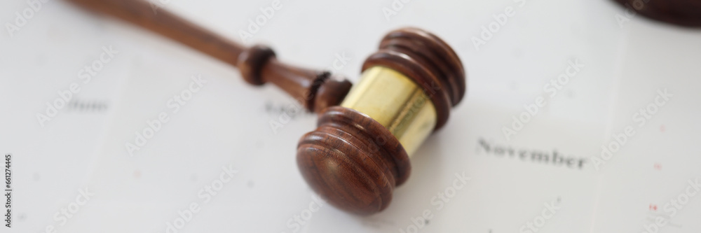 Wooden judge gavel and sound block lie on calendar paper Wooden judge gavel and sound block lie on calendar paper