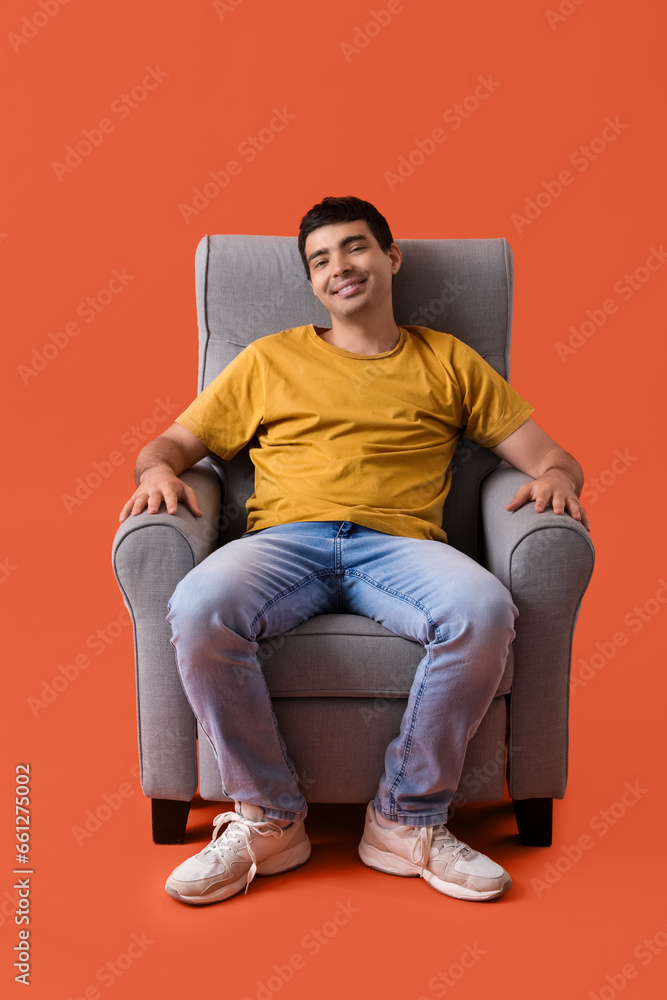 Young man sitting in armchair on red background Young man sitting in armchair on red background