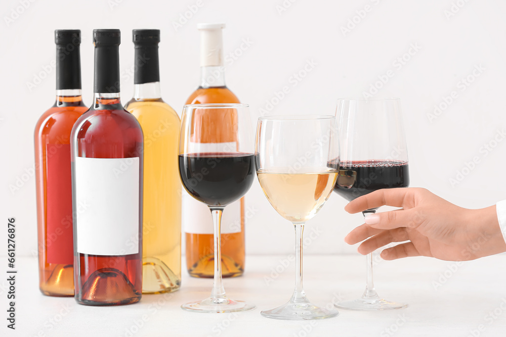 Female hand and glasses of different exquisite wine on light background