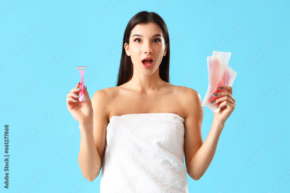 Shocked young woman with razor and wax strips on blue background Shocked young woman with razor and wax strips on blue background