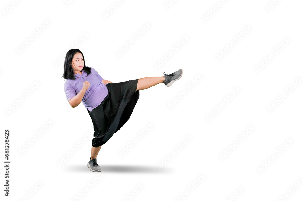 Full length portrait of an overweight woman kicking isolated on white background