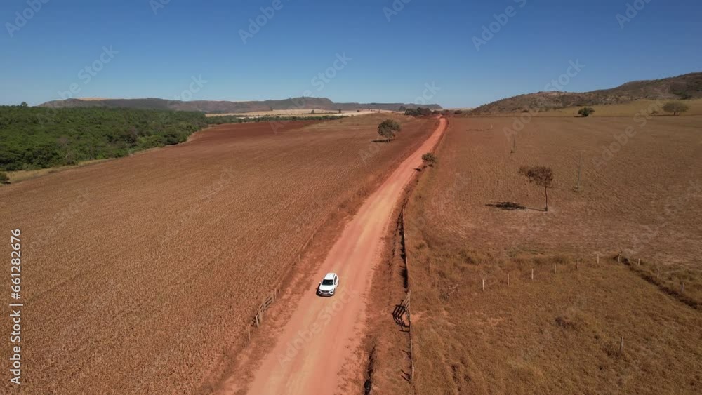 drone view of a moving car raising dust on a dirt road in Chapada dos Veadeiros, Goiás, Brazil sunny day