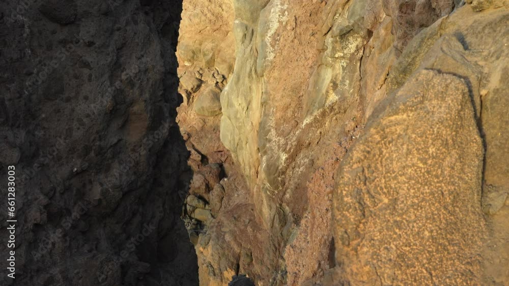 Sunlight shines on rocky cliff coast at golden hour, close up, tilt up, Tenerife Sunlight shines on rocky cliff coast at golden hour, close up, tilt up, Tenerife