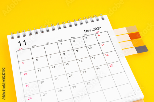 The November 2023 Monthly desk calendar and blank adhesive note on yellow background.