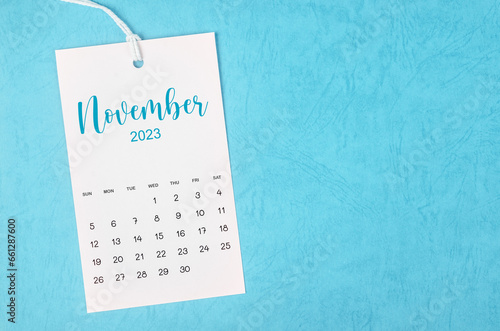 The 2023 November calendar page hanged on white rope  on blue background.