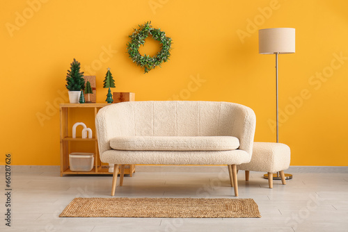 Interior of festive living room with white sofa  wooden shelving unit and Christmas decorations