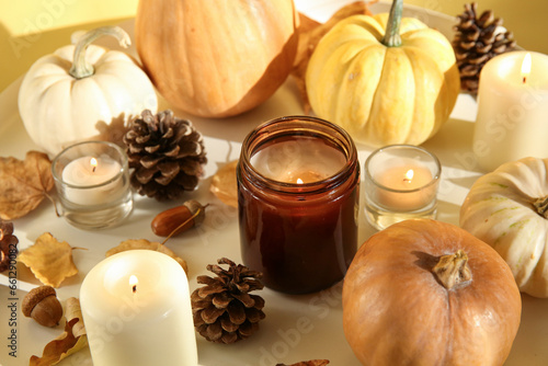 Burning candles  pumpkins  pine cones and autumn leaves on table