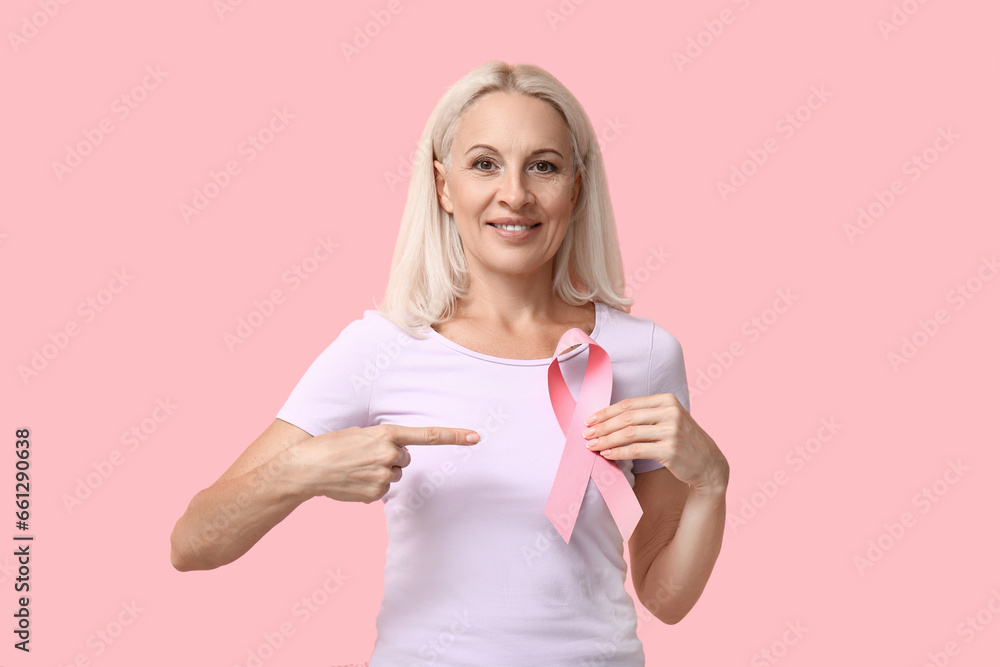 Mature woman with ribbon on pink background. Breast cancer awareness concept Mature woman with ribbon on pink background. Breast cancer awareness concept