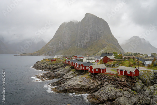 Eliassen Rorbuer in the fishing village of Hamnoy, Norway, in the Lofoten Islands. The red fishing cabins sit in dramatic contrast to the rugged rocky seaside cliffs and are now used for tourism.