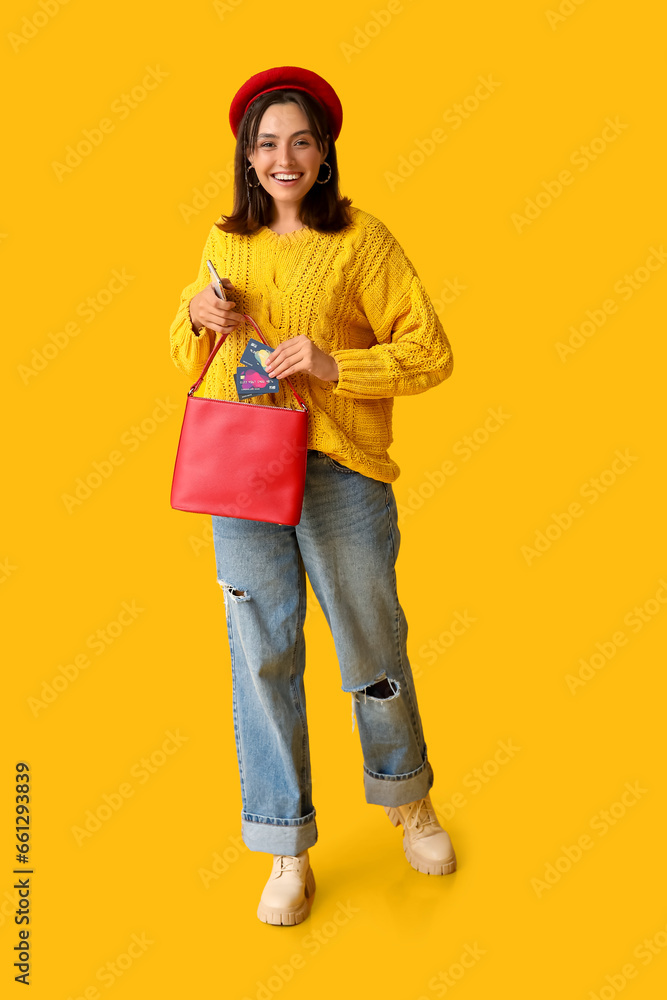 Young woman with credit cards, mobile phone and stylish bag on yellow background Young woman with credit cards, mobile phone and stylish bag on yellow background