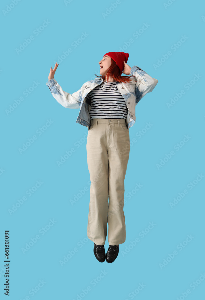 Obraz premium Jumping young woman in autumn clothes on blue background