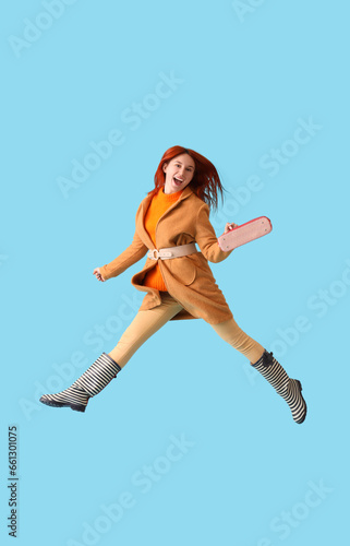 Jumping young woman in autumn clothes on blue background