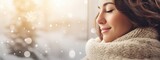 Adult caucasian woman in a warm sweater with closed eyes against a winter landscape and shimmering snowflakes. A Christmas and New Year background. Banner with copy space.