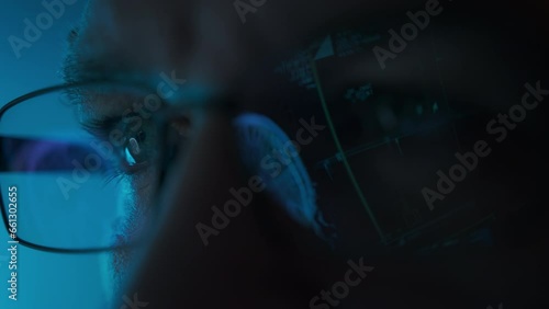 Male doctor eyes in eyeglasses late at night looking in front of MRI data on laptop. Macro shot photo