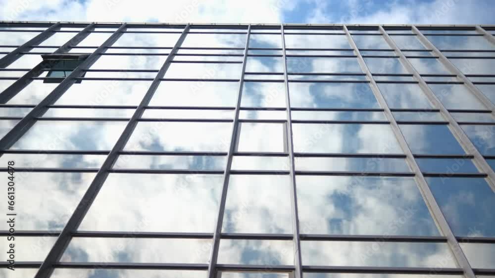 Smooth camera movement in front of the windows of an office building reflecting a sunny blue sky with white puffy clouds. 4k Smooth camera movement in front of the windows of an office building reflecting a sunny blue sky with white puffy clouds. 4k
